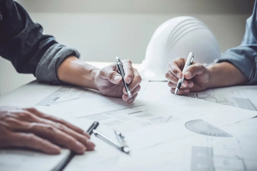 Project team reviewing construction drawings beside a hard hat