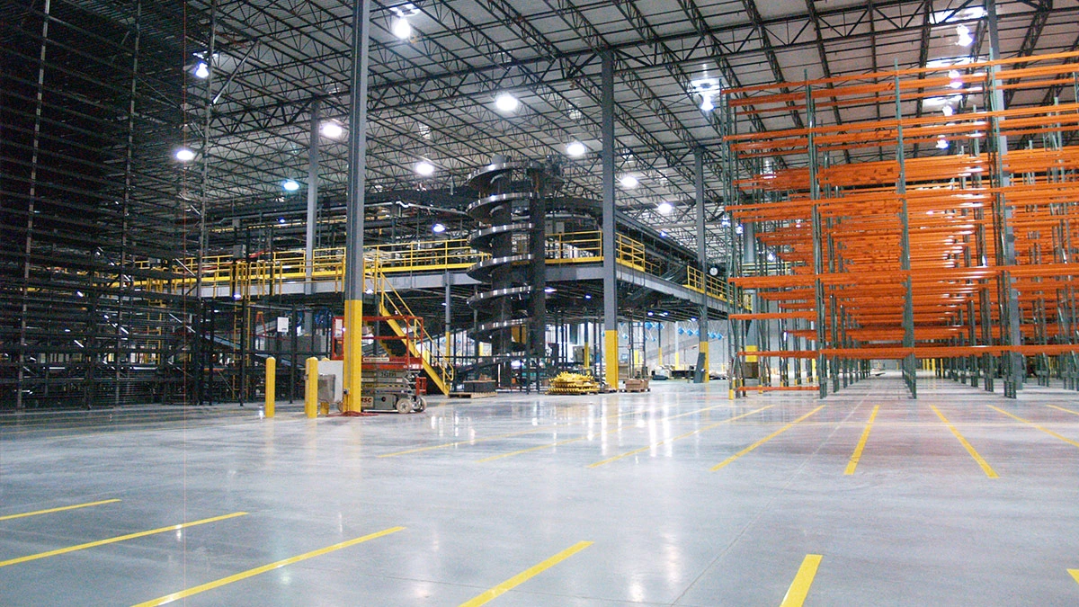 Warehouse interior with orange pallet racks, a mezzanine and yellow floor markings